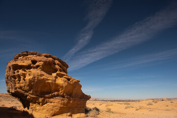 A rock looking like a gigantic skull against a blue sky and clouds in Hegra near Al Ula Saudi Arabia