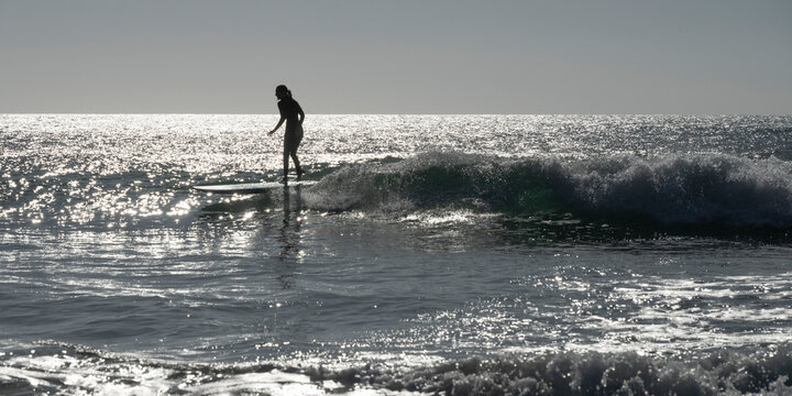 Surfing on the shimmering water along the Sagres Beaches of Portugal. Sagres sits at the extreme western tip of the Algarve region; Sagres, Faro, Portugal