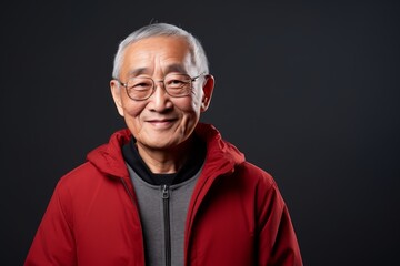 Obraz premium Portrait of a glad asian man in his 80s wearing a zip-up fleece hoodie isolated in empty modern loft background