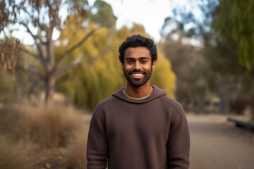 Fototapeta premium Portrait of a satisfied indian man in his 20s wearing a cozy sweater in empty modern loft background