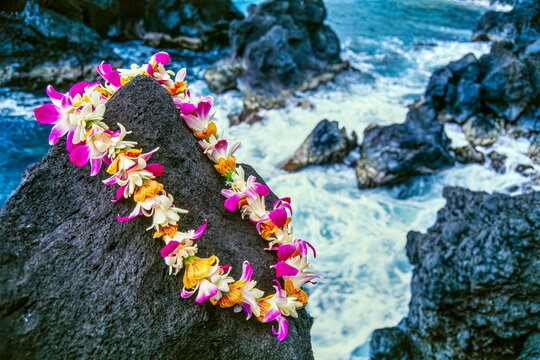 Flower lei on lava rock with ocean background, Hawaii, USA; Hawaii, United States of America