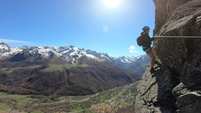 Ragazza che arrampica su panoramica via ferrata in montagna nelle alpi, giornata di sole, cielo blu