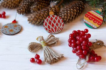 DIY decorations for Christmas. Xmas card. Christmas composition with Ukrainian doll-motanka, wooden balls, guelder rose, cones and fir branches. New Year eco-conscious handmade toys. Happy holidays.