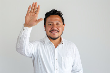 Fototapeta premium Happy Mexican man warmly welcomes friends in front of the camera, offering a friendly wave and a genuine smile against a neutral white backdrop.
