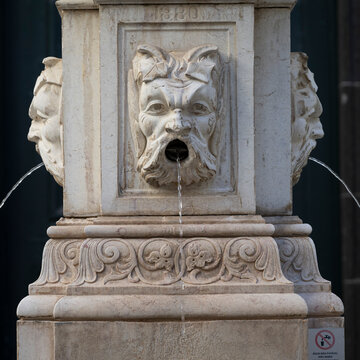 Water flowing from the mouths of men on a stone fountain in Portugal; Funchal, Madeira, Portugal