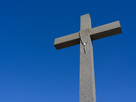 Close-up of stone cross against a bright, blue sky in C&acirc;mara de Lobos, a  de facto suburb of the capital city of Funchal; C&acirc;mara de Lobos, Madeira, Portugal