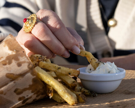 Woman's hand dipping a french fry into a sauce; Madeira, Portugal