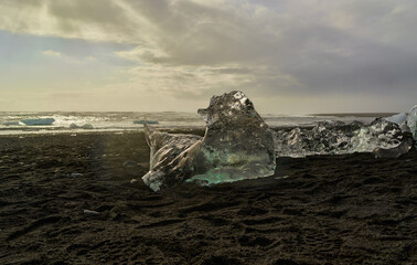 Large iceberg melting on volcanic black sand beach
