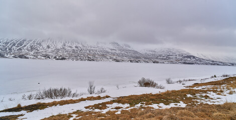 Frozen lake surrounded by snow covered mountains in winter