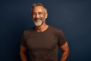 Fototapeta premium Portrait of a smiling man in his 50s donning a trendy cropped top isolated on plain cyclorama studio wall