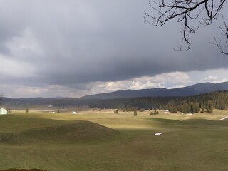 Green and yellow hilly landscape under cloudy ceiling with sun breaking through