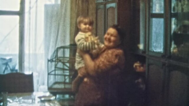 Happy grandmother holding granddaughter in arms in room indoors. Smiling granny proud of heiress child. Cheerful senior woman portrait. Vintage color film. Family happiness archive. Retro 1980s. 4k