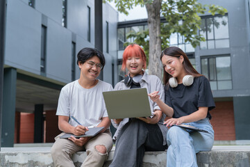 Three cheerful young students are sitting together outdoors, engaged in a collaborative project using a laptop, fostering teamwork and knowledge sharing in a vibrant learning environment