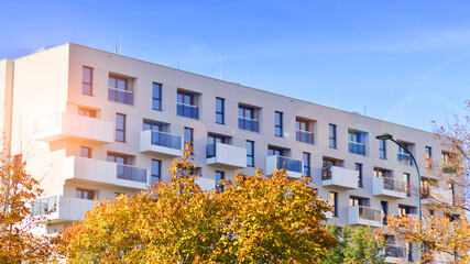 Modern residential building with new apartments in a green residential area. Eco architecture. Yellow tree and new apartment building. The harmony of nature and modernity.