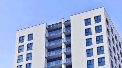 Modern high-rise apartment building  in white, stand tall against a blue sky, exemplifying innovative urban architecture with sleek, angular designs.