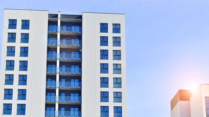 Modern high-rise apartment building  in white, stand tall against a blue sky, exemplifying...