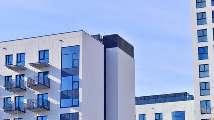 Modern high-rise apartment building  in white, stand tall against a blue sky, exemplifying...