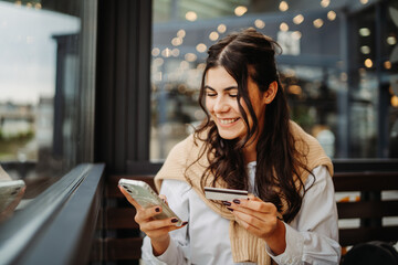 Young caucasian woman using credit card to buy online on her phone	
