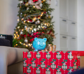 Blue piggy bank front of a Christmas tree decorated with beautiful Christmas vibes. Holiday season in December for family and friends together and give a gift and using money. saving money for present