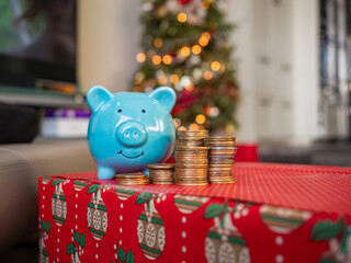 Blue piggy bank front of a Christmas tree decorated with beautiful Christmas vibes. Holiday season in December for family and friends together and give a gift and using money. saving money for present