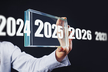  Woman hold the button with number 2025 - copy space and bokeh for preparation merry Christmas and happy new year. Digital business calendar.