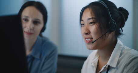 Online customer service: Close up of two female technical support operators in headsets consulting...