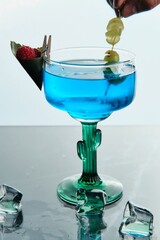 Blue Cocktail with Raspberry and Grape Garnish