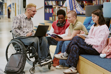 Group of diverse young individuals engaging with technology and books in contemporary library....