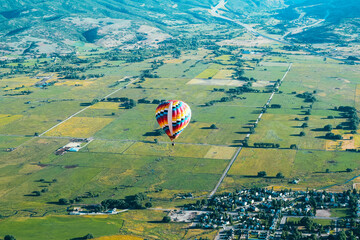 Aerial photo of a Beautiful, Colorful hot air balloon, flying above the vast green fields of Park City, Utah, USA