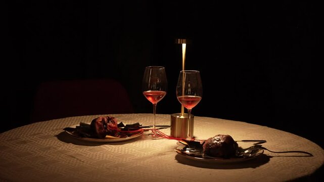 Unusual round table setting for two lovers on a romantic date. Two hearts on plates are intertwined with a red line of love. Dinner for two by candlelight. Horror. High quality 4k footage