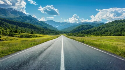Naklejka premium A wide road leading into the distance, with green mountains and forests on both sides of it