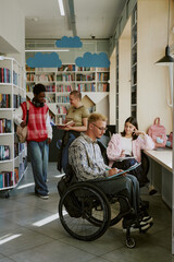 Group of students studying in a modern library with cloud-themed decor, with one student in a...