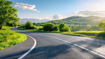 Fototapeta premium A scenic road winding through the mountains, with trees and grass on both sides of it