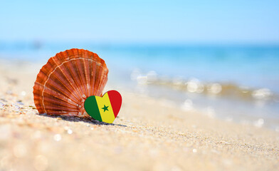 Sandy beach in Senegal. Senegal flag in the shape of a heart and a large shell.