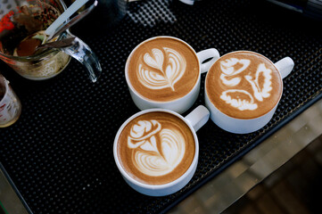 Three latte art cups with different designs.Using skills in making latte menus.Drink coffee in the...