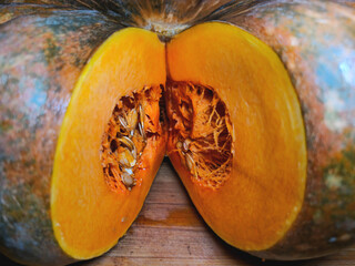 Close-up of a cut pumpkin. Pumpkin seeds inside. Cut pumpkin on a wooden board.