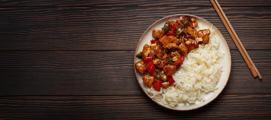 Steaming Chinese kung pao chicken with rice, veggies, and peanuts in spicy sauce. Top view on...
