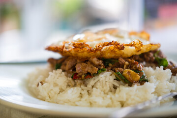 A plate of spicy basil stir fry with pork, topped with a crispy fried egg stunning presentation