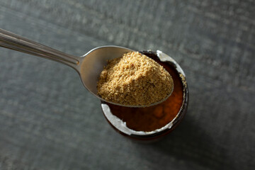 A top down view of a spoon scooping some beef bouillon from the container.