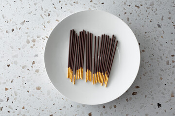 A top down view of a plate of chocolate covered biscuit sticks.