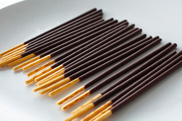 A closeup view of a plate of chocolate covered biscuit sticks.