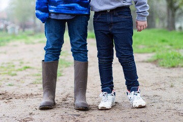 two kids legs standing in the mud