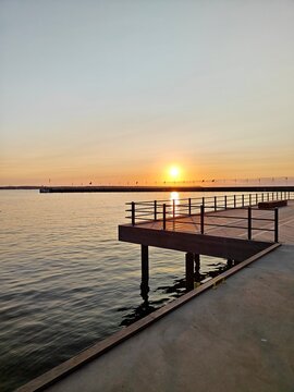 A serene sunset in Helsingborg over the water, with a wooden pier extending into the calm sea, creating a peaceful and scenic view