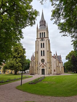 beautiful, historic church with a tall spire, surrounded by lush greenery and pathways, creating a tranquil and picturesque setting