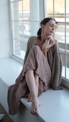 Beautiful young girl posing for the camera while sitting near a large window