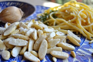 Fresh ingredients for a delicious pasta dish with pine nuts and garlic on a blue plate