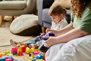 A mother and daughter enjoy creative play with vibrant building blocks in their cozy living room.