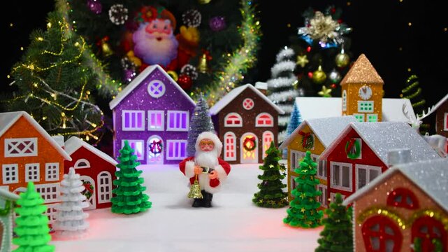 Against the backdrop of a Christmas wreath is a beautiful large Christmas town with Christmas trees, houses and Santa Claus