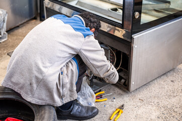 An electrician fixing an electrical device in a workshop.