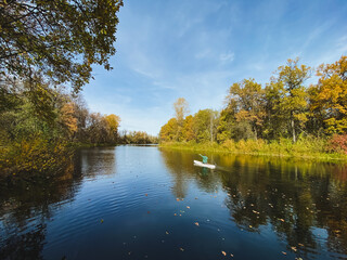 A person is paddling a kayak on a lake surrounded by trees